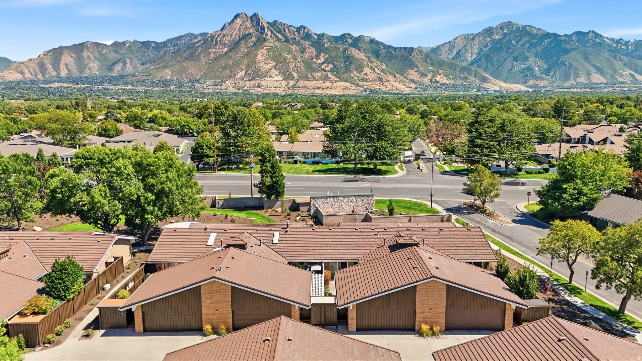 Brown-toned roofs, brick accents, ample mature trees, and mountainous terrain