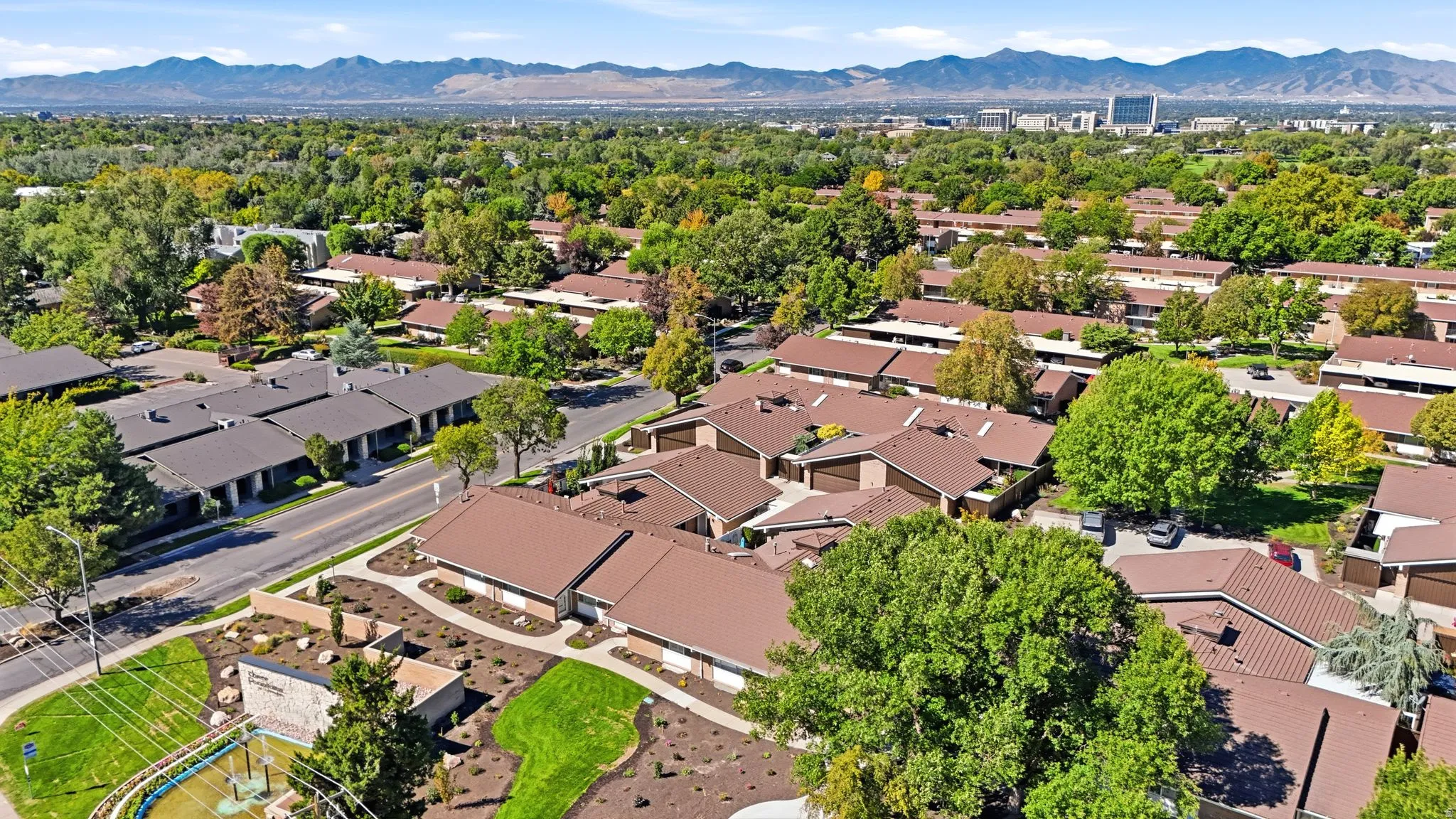 Expansive community featuring multiple residential buildings with brown roofs, mature trees, and landscaped common areas