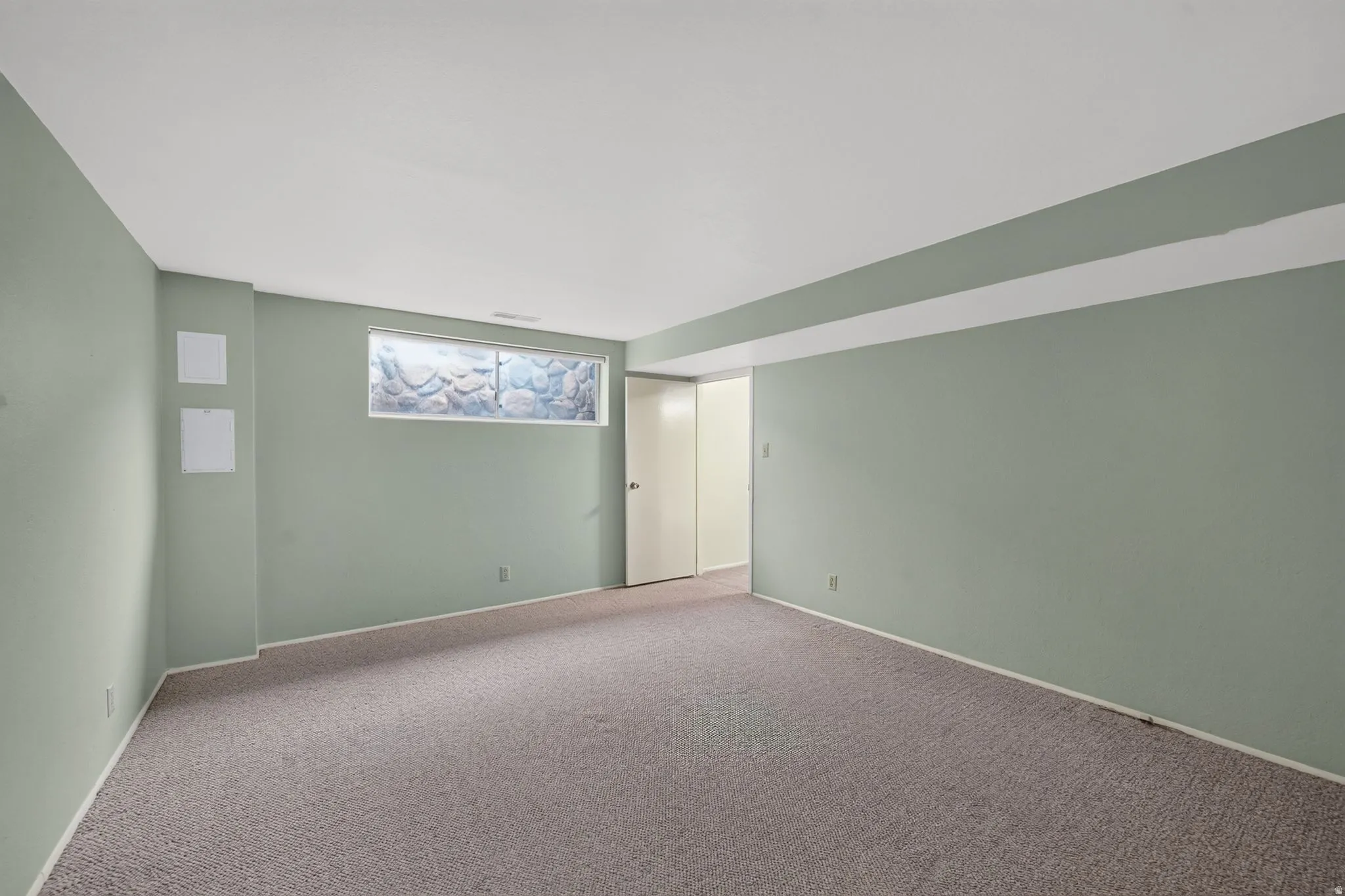 Carpeted flooring, light green wall paint, interior door, window, and white ceiling