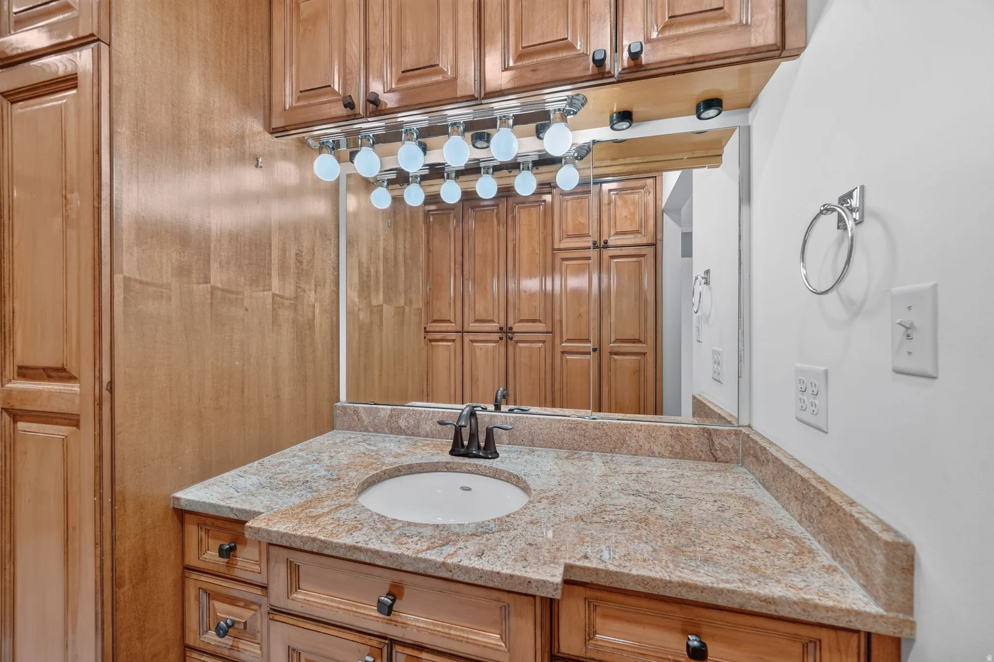 Vanity featuring a built-in sink, granite countertop, and wood-finish cabinetry