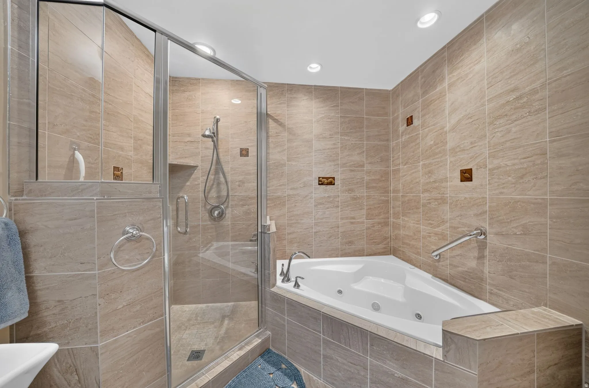 Tiled bathroom featuring a glass-enclosed shower, a corner jetted tub, and recessed lighting