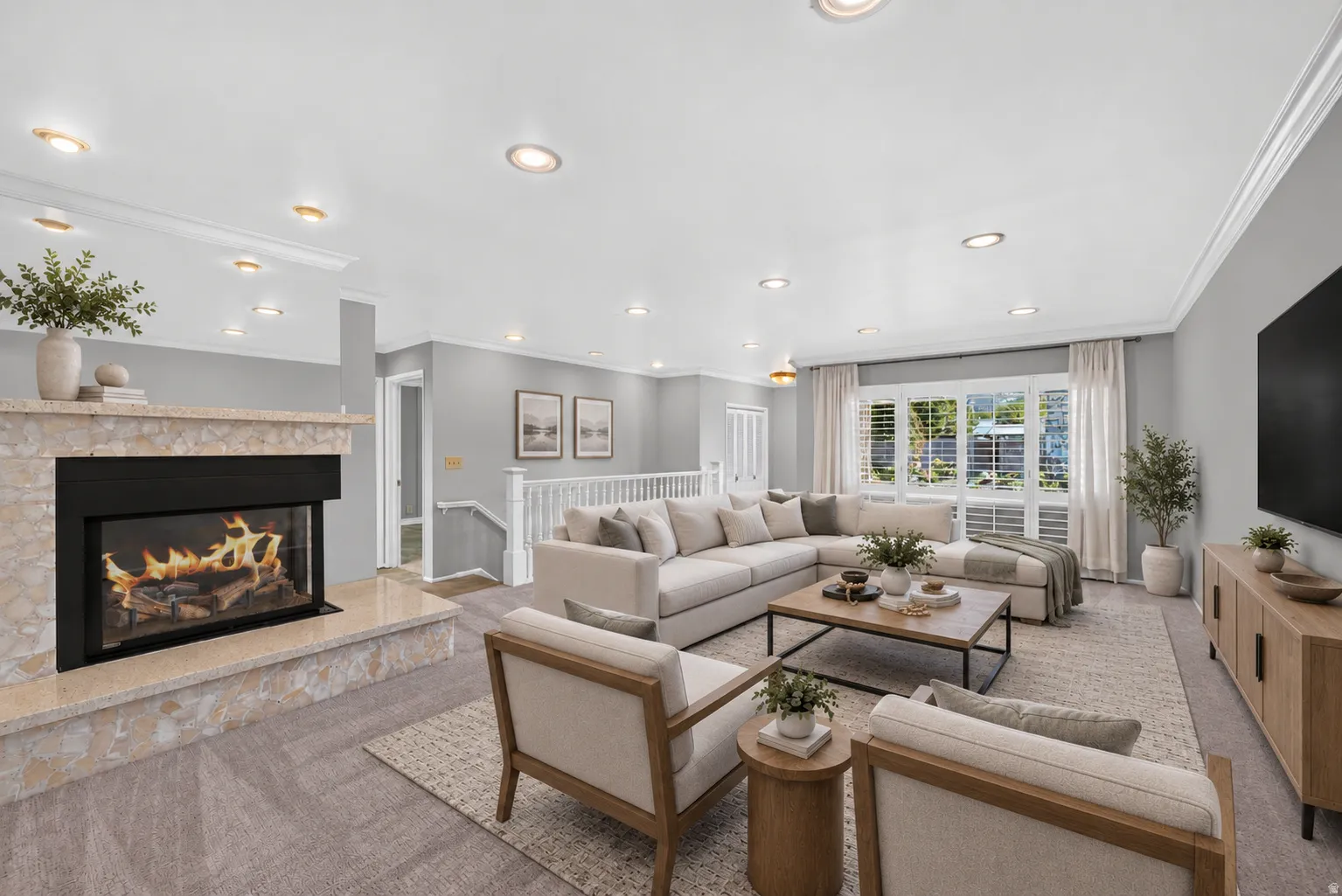 Recessed lighting, crown molding, and a stone-clad fireplace with a raised hearth