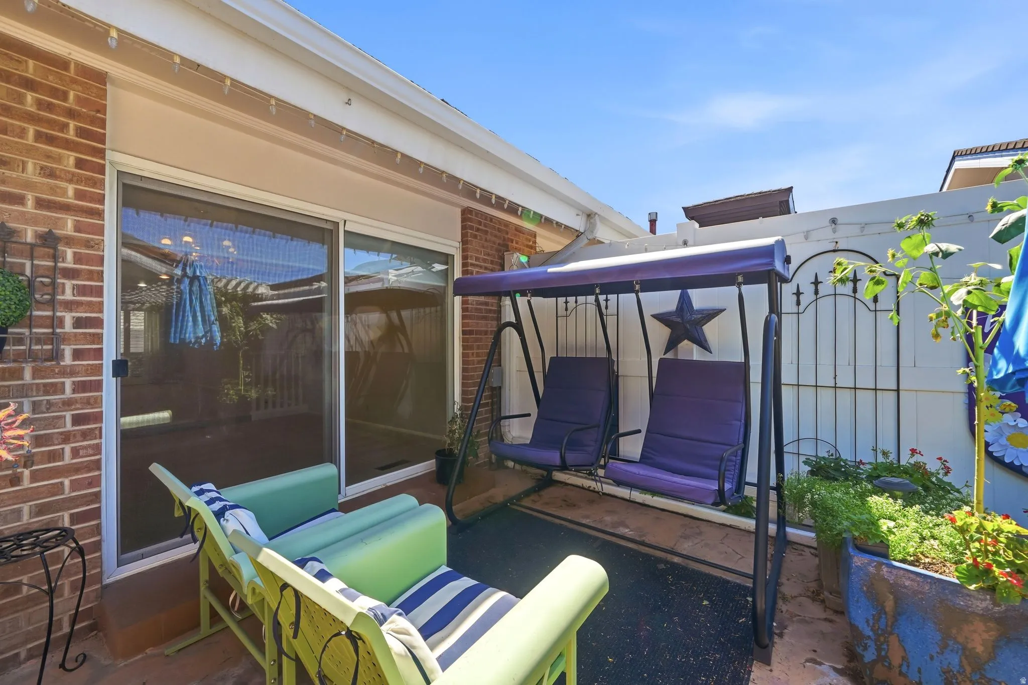 Brick exterior with a sliding glass door, paved patio, and a white privacy fence
