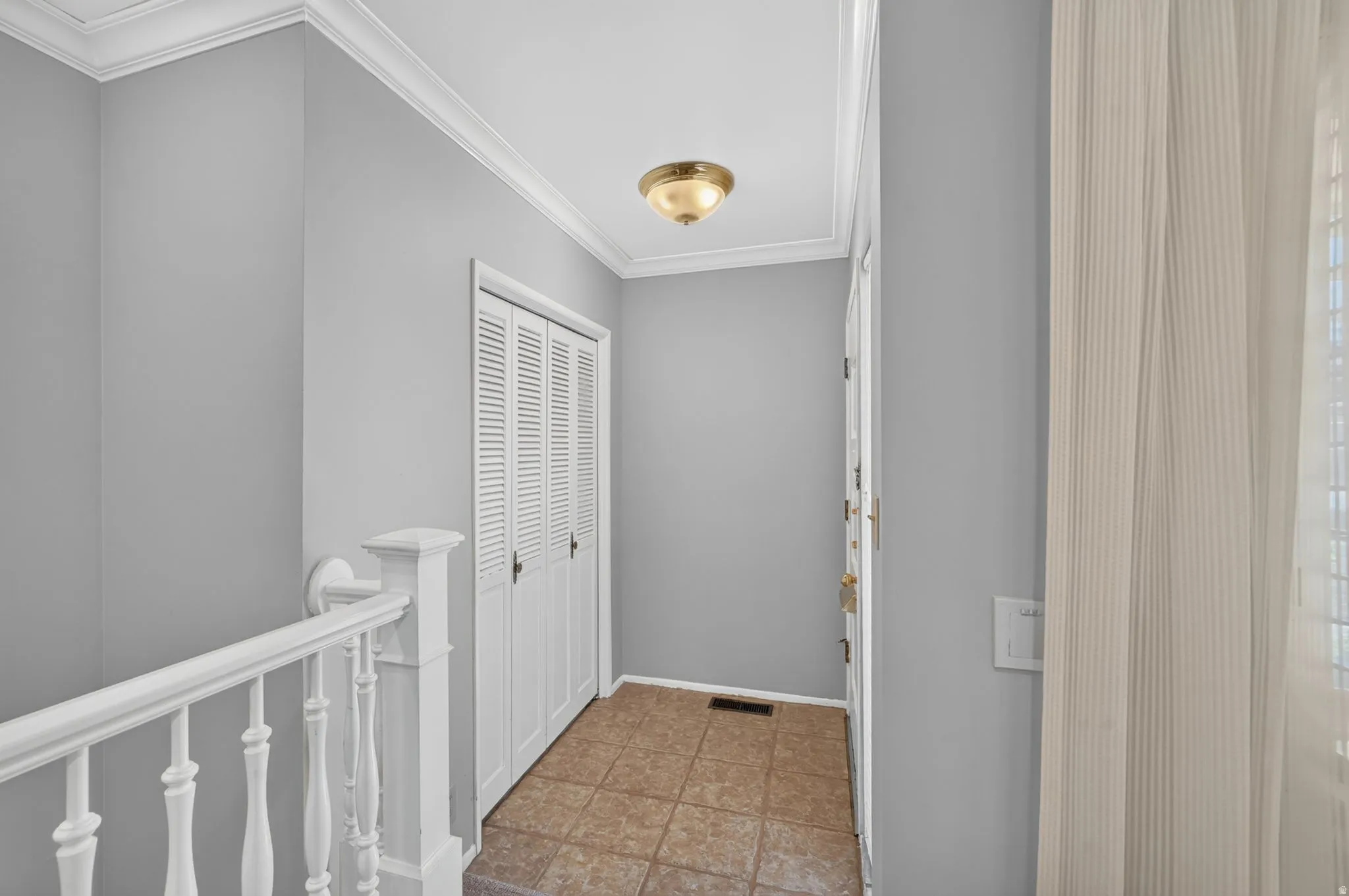 Crown molding with recessed ceiling light, louvered bi-fold closet doors, and ceramic tile flooring