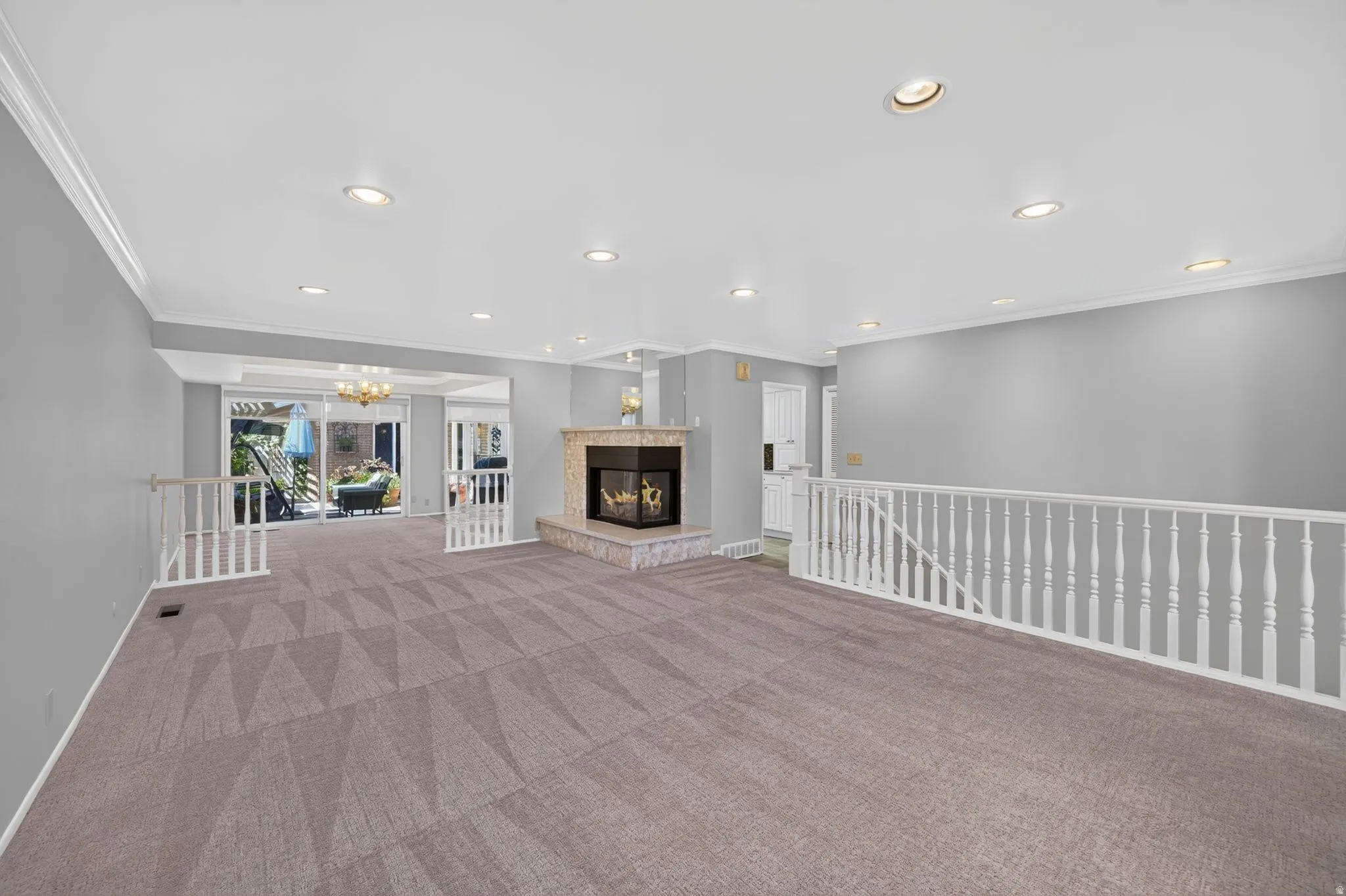Recessed lighting, crown molding, a gas fireplace with stone surround, and carpet flooring
