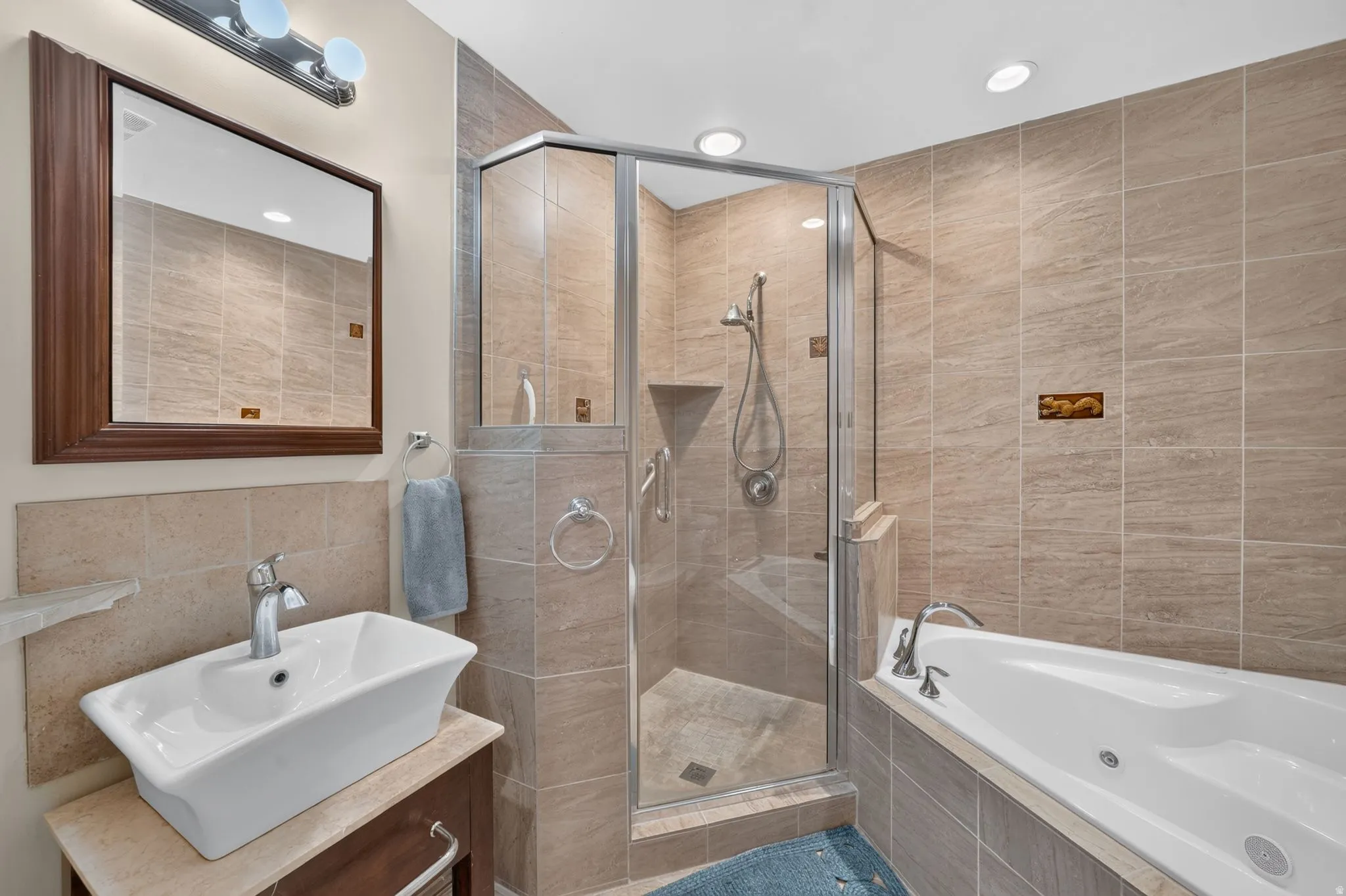 Tiled bathroom featuring a glass-enclosed shower, built-in bathtub, vessel sink, and recessed lighting