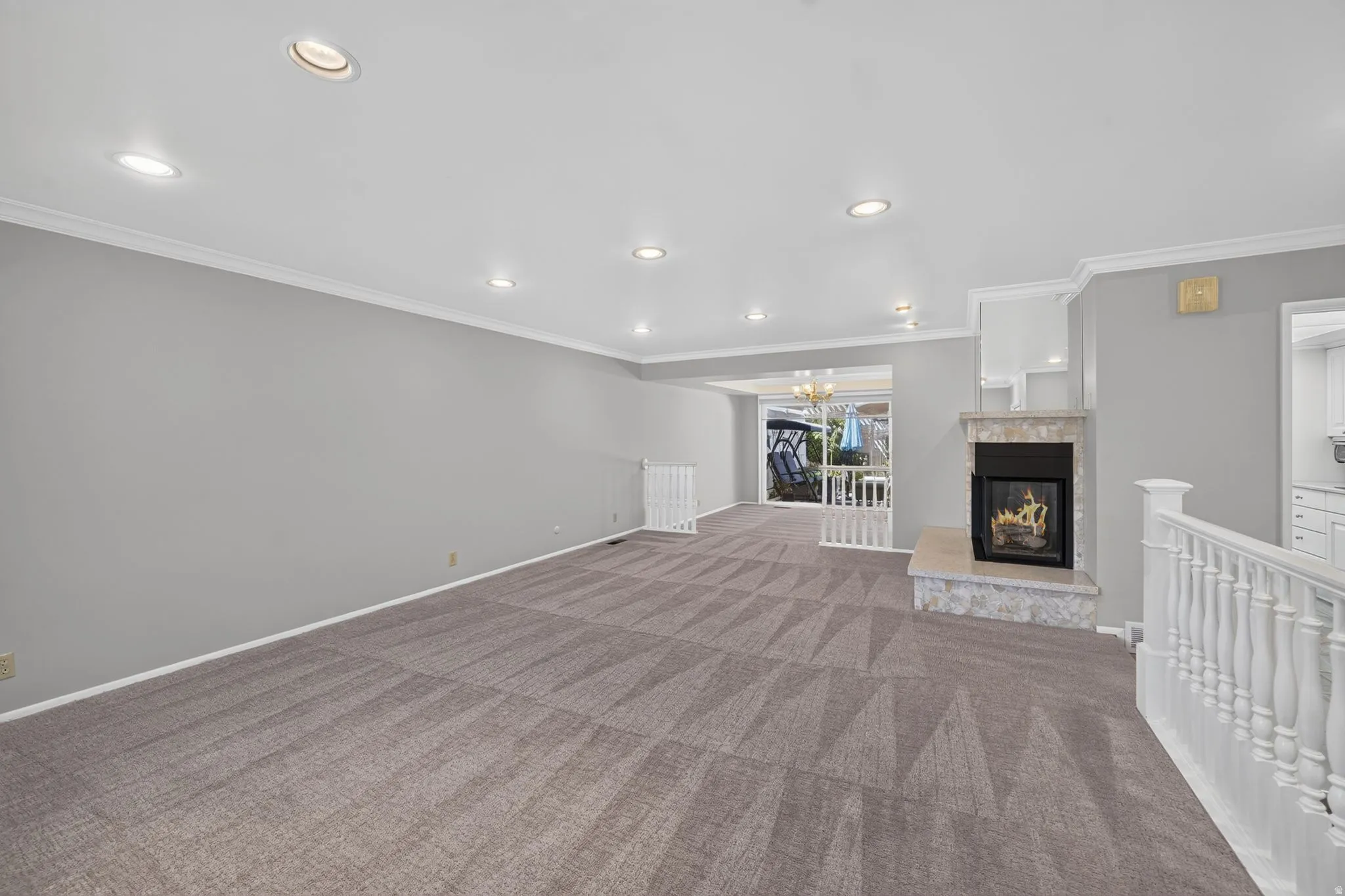 Recessed lighting, crown molding, and neutral wall tones complement the patterned carpeting