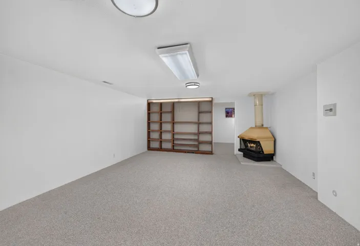 Wall-to-wall carpeting with built-in shelving, a free-standing fireplace, and recessed lighting