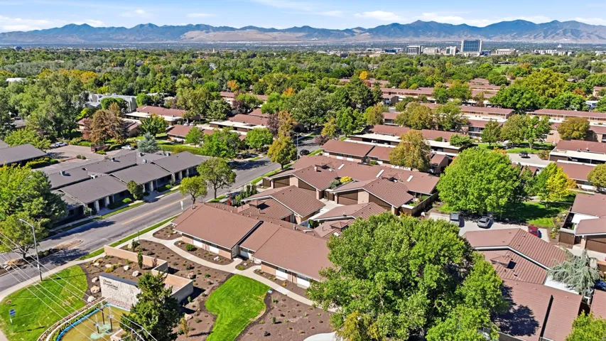Expansive community featuring multiple residential buildings with brown roofs, mature trees, and landscaped common areas