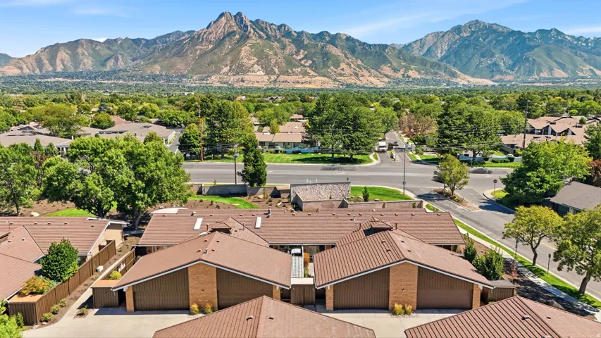 Brown-toned roofs, brick accents, ample mature trees, and mountainous terrain