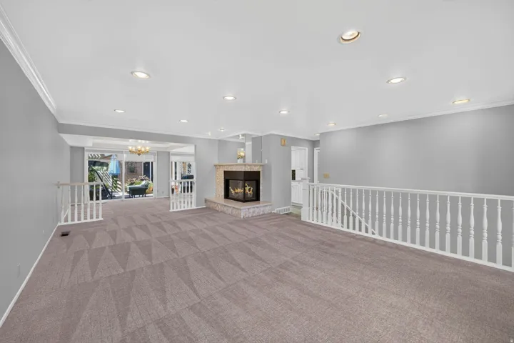 Recessed lighting, crown molding, a gas fireplace with stone surround, and carpet flooring