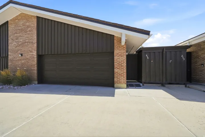 Brick facade with vertical paneling, attached garage, and a concrete driveway