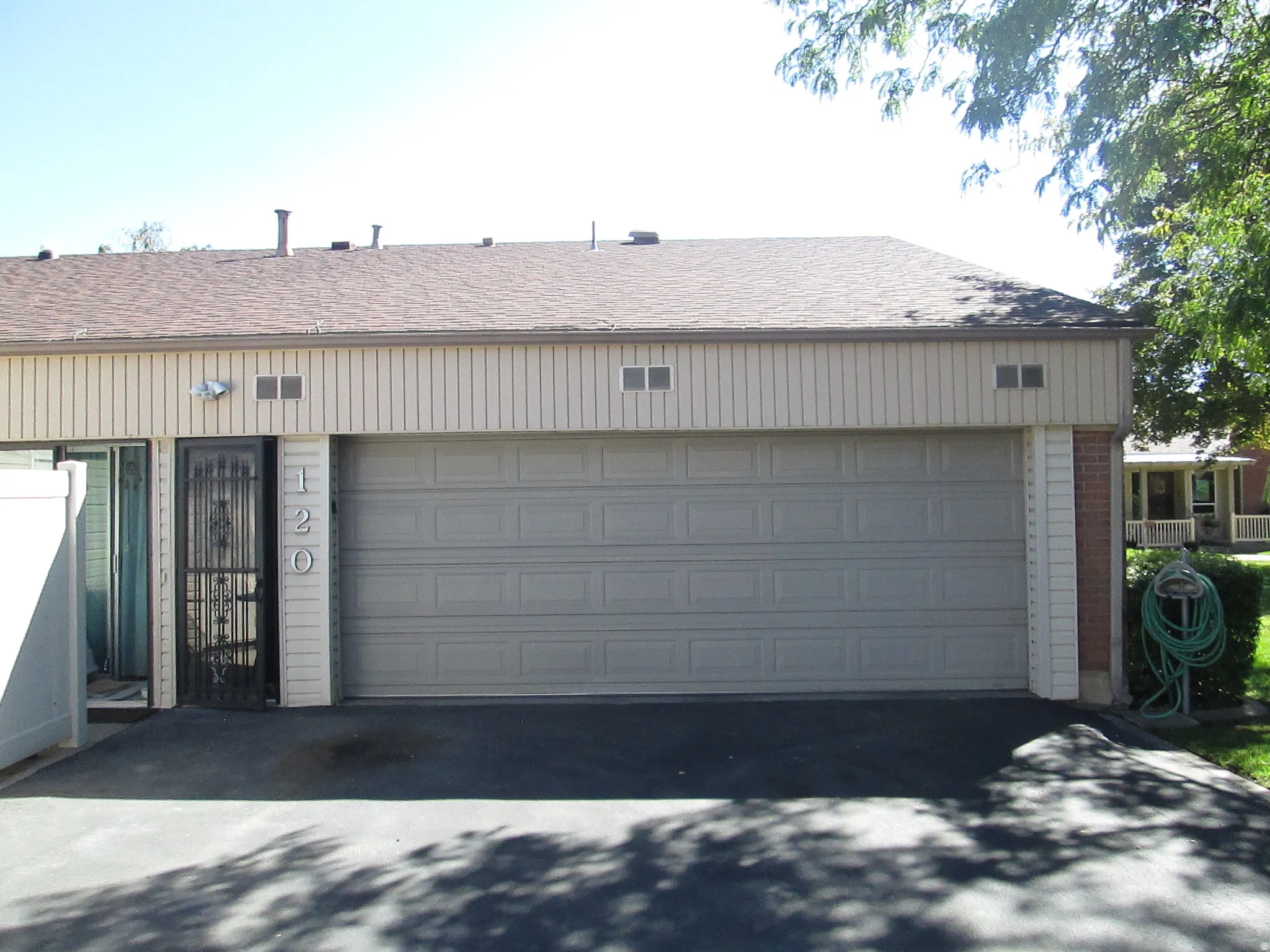 Attached two-car garage with paneling, asphalt driveway, and brick accent columns