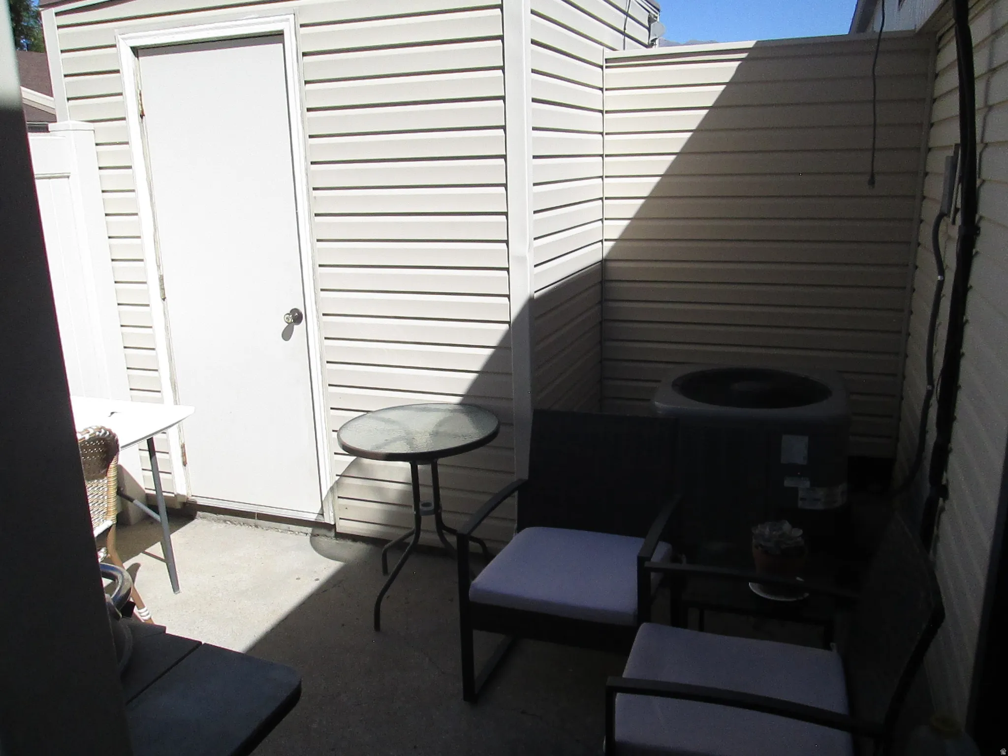 Private outdoor patio with concrete flooring, accented by horizontal vinyl siding