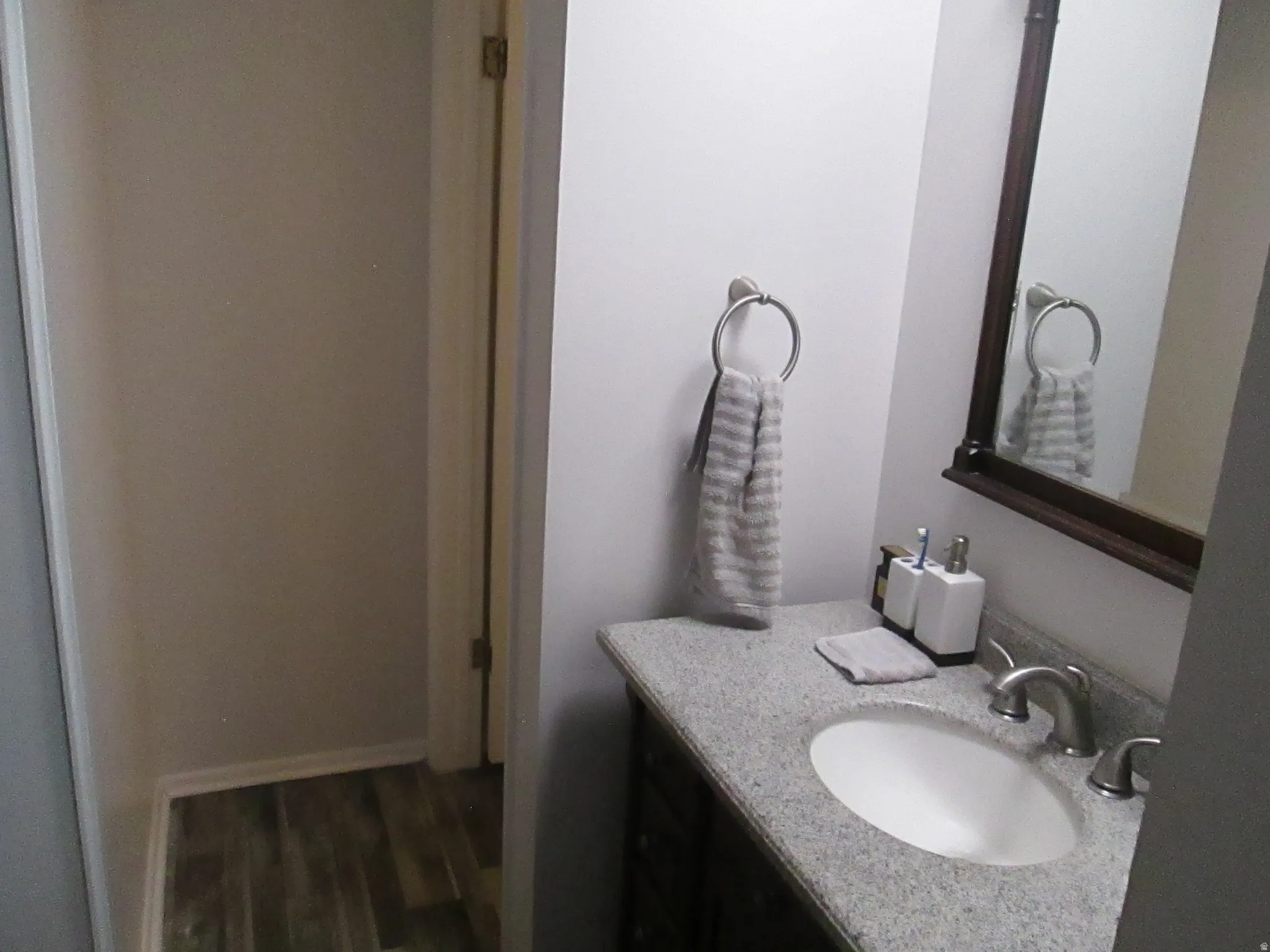 Vanity with an oval undermount sink, dual-handle faucet, and granite-style countertop