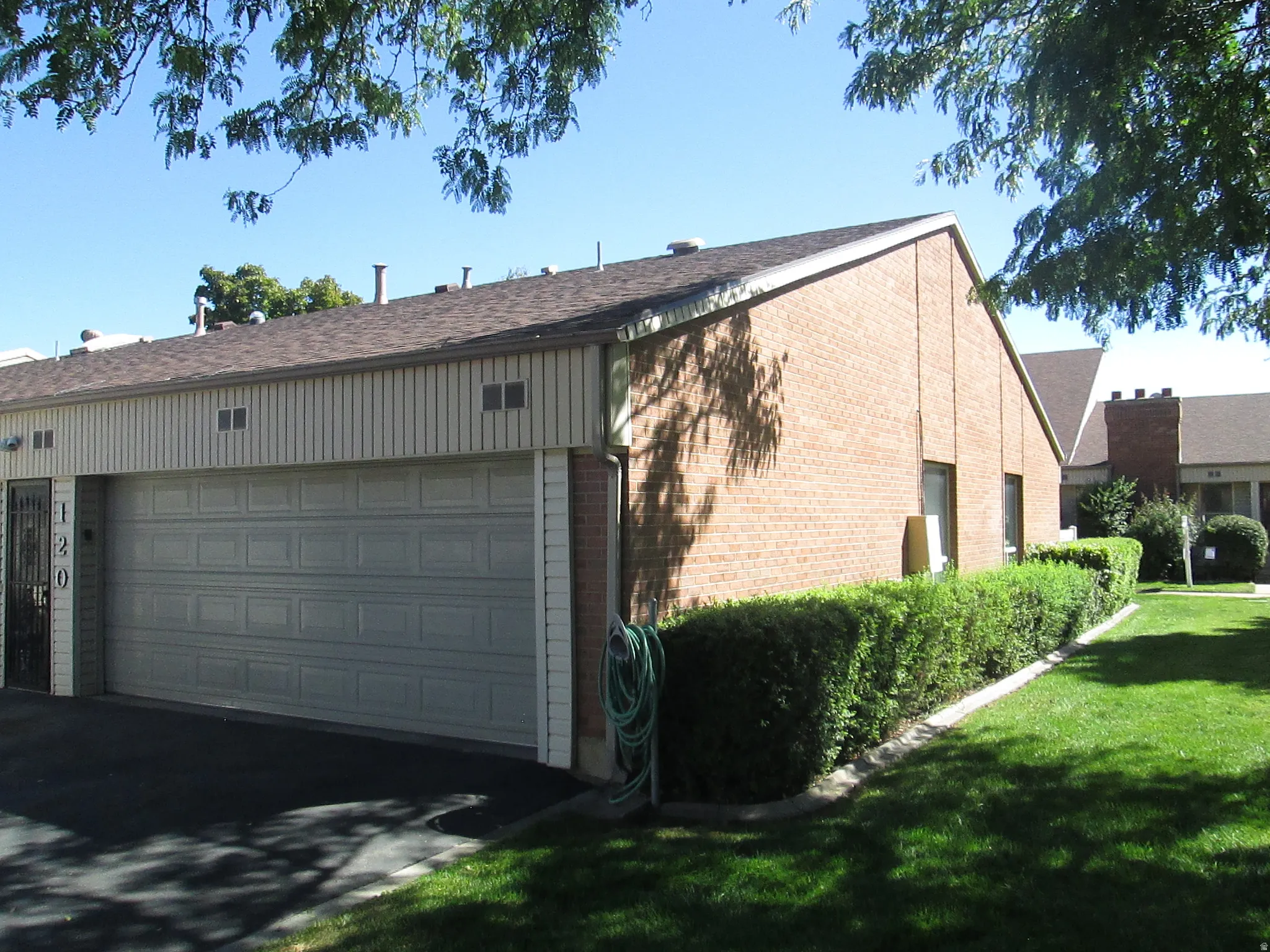Brick exterior with a peaked roof, two-car garage, and mature landscaping