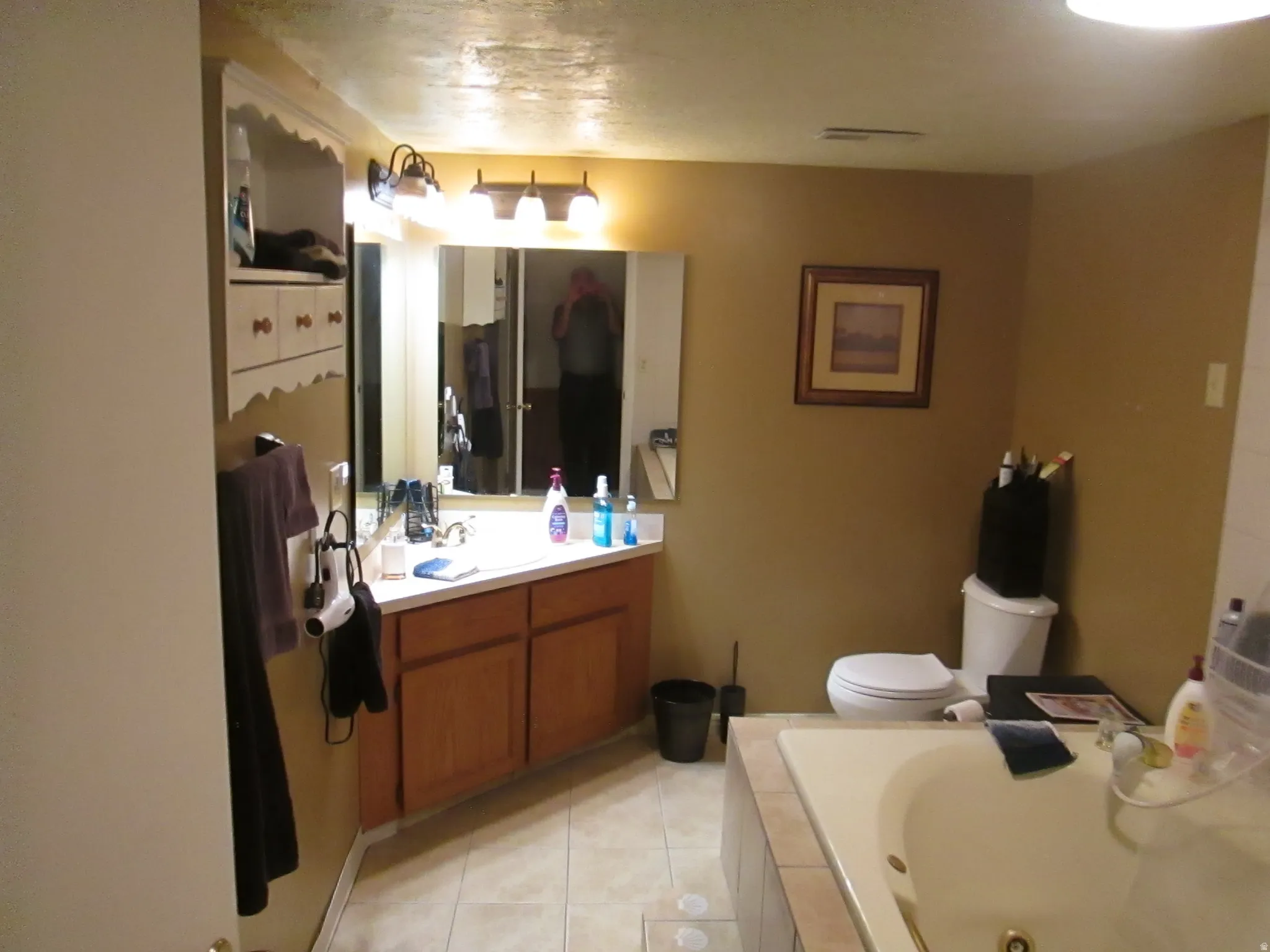Ceramic tile flooring, built-in shelving, wood-finish vanity with countertop, and a built-in tub