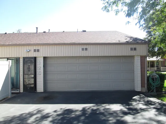 Attached two-car garage with paneling, asphalt driveway, and brick accent columns