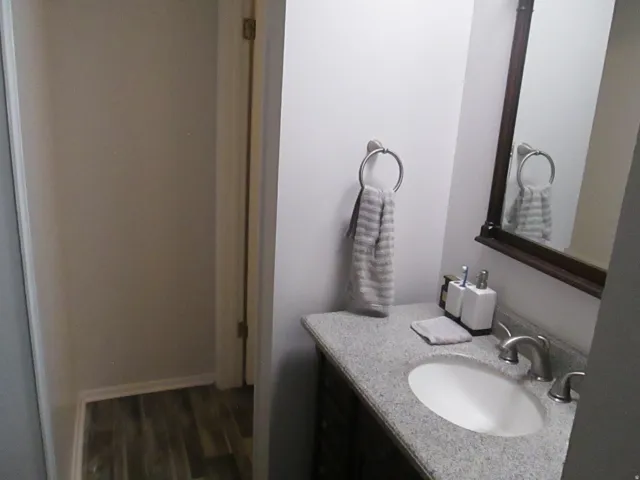 Vanity with an oval undermount sink, dual-handle faucet, and granite-style countertop