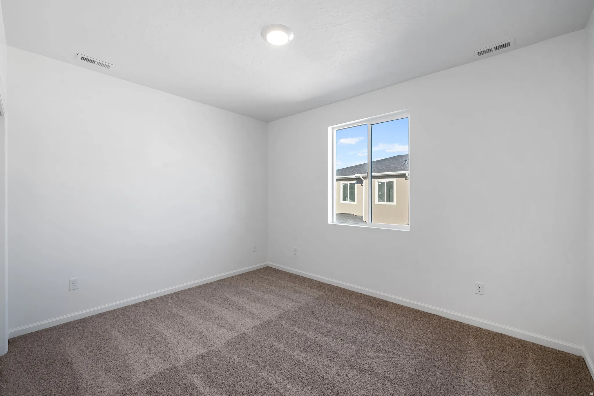 Neutral wall colors, recessed ceiling lighting, a single window, and textured carpeting