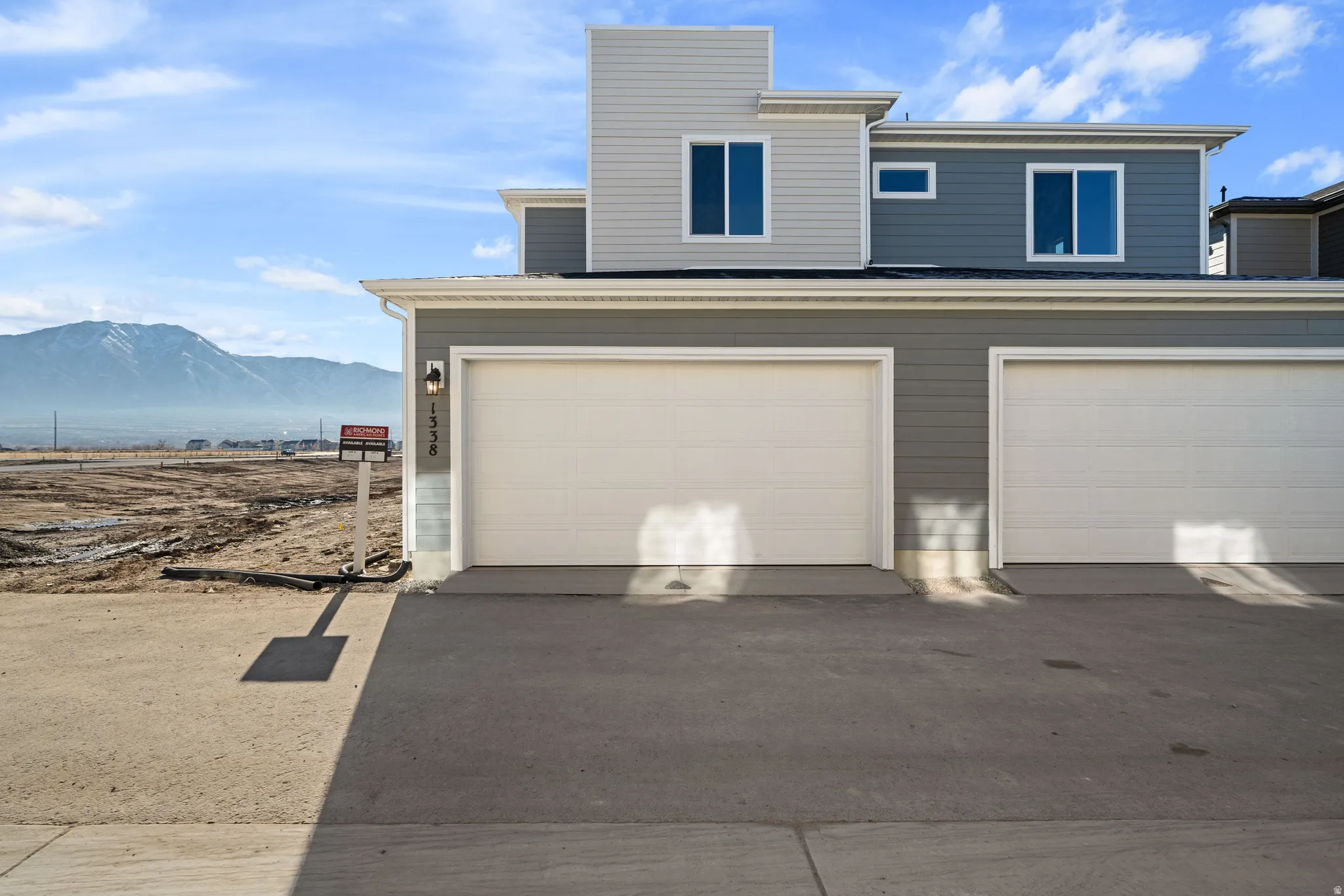 Modern exterior with multi-toned siding, two attached garage doors, and multiple windows