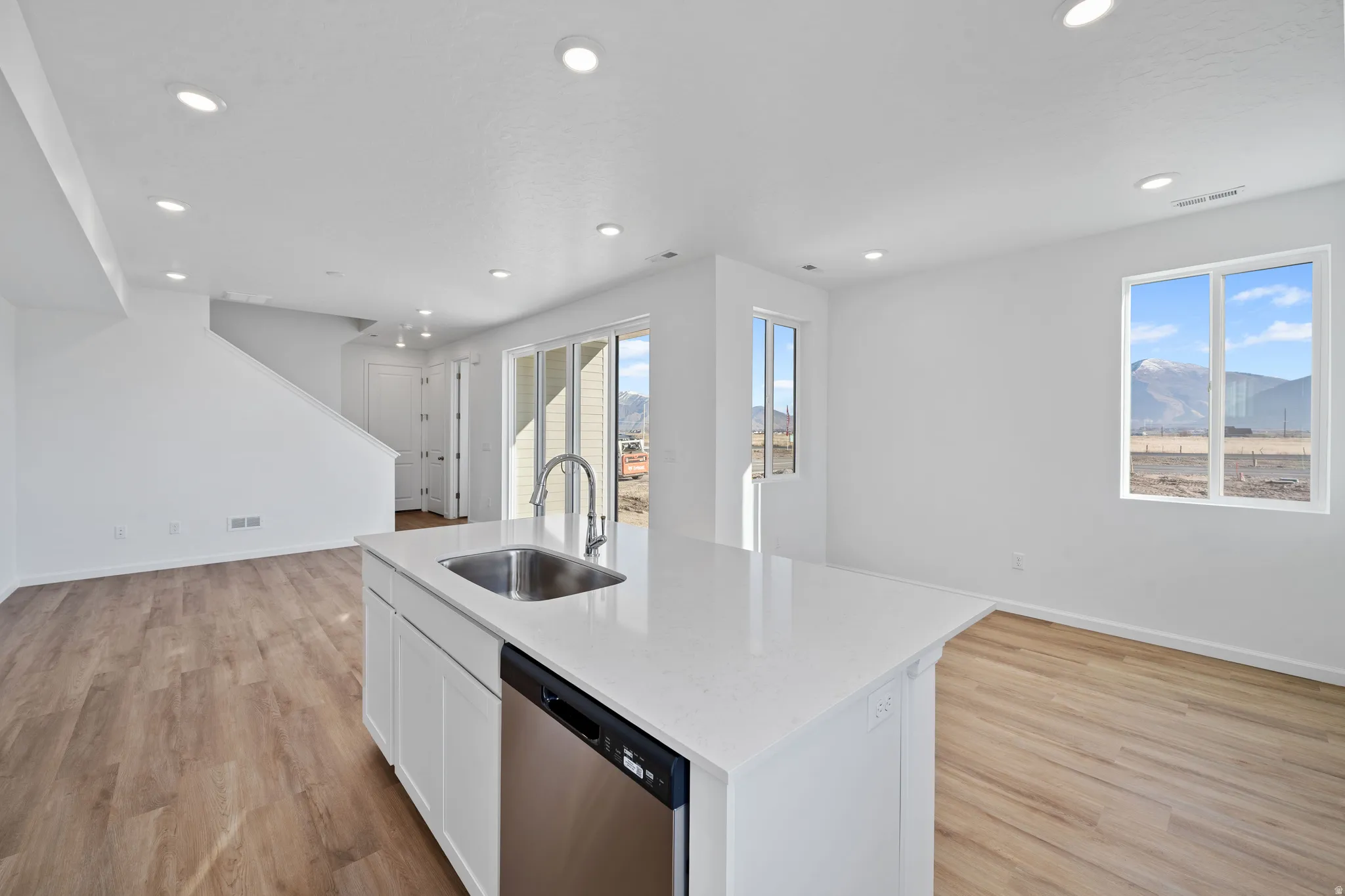 Kitchen island with a stainless-steel sink and faucet, integrated dishwasher, and a light-toned countertop
