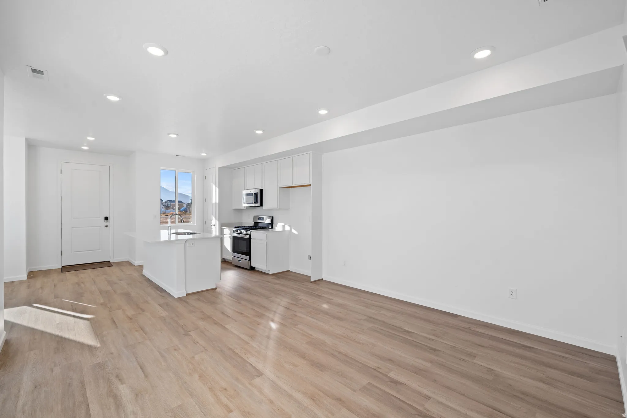 Open-concept living space with wood-finish flooring, recessed lighting, and a white kitchen island