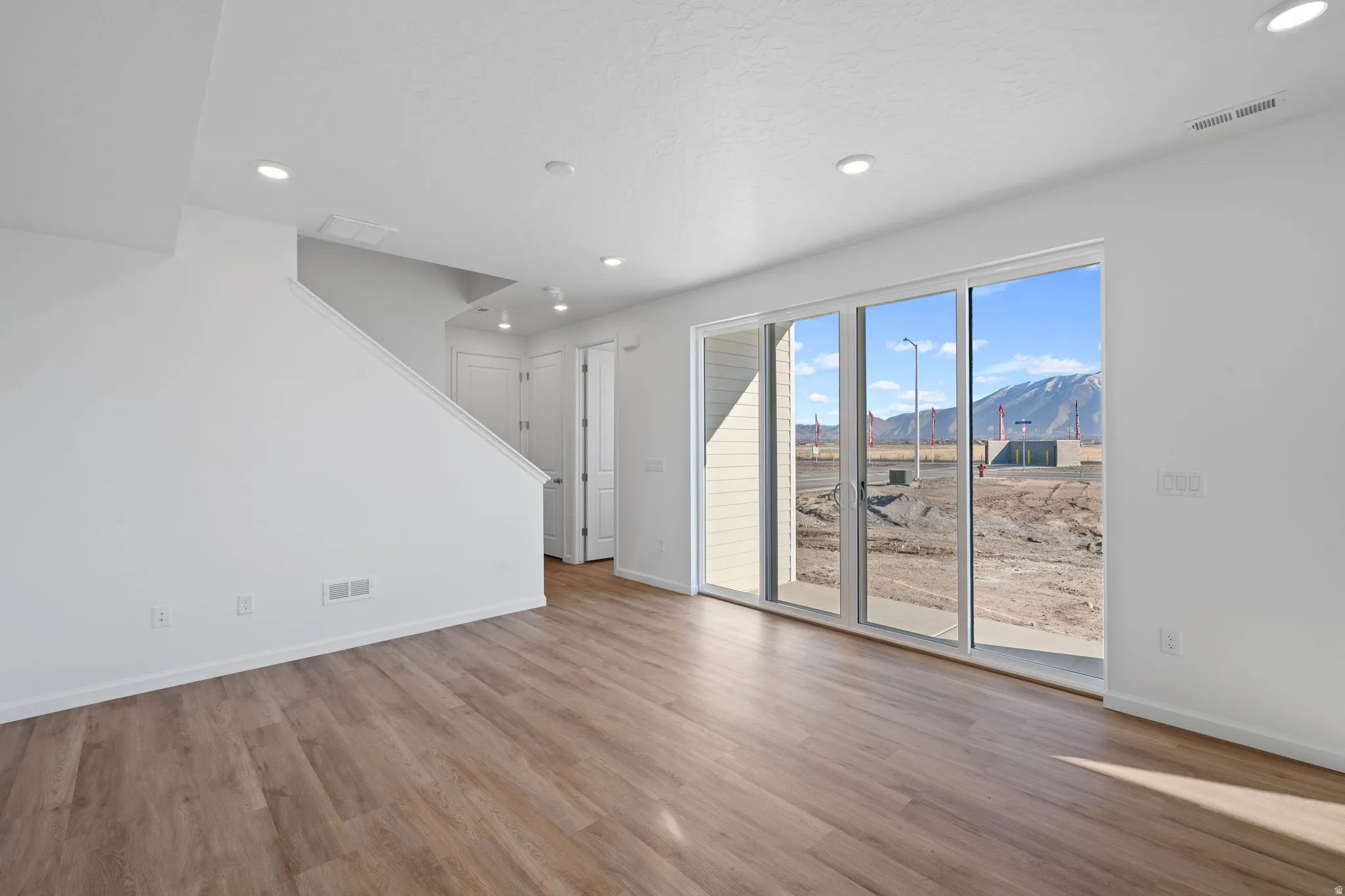 Spacious room featuring wood-finish flooring, recessed lighting, and a large sliding glass door