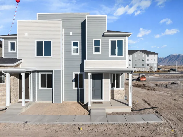 Contemporary exterior with multi-toned siding, stone veneer accents, white trim details, and a covered entry
