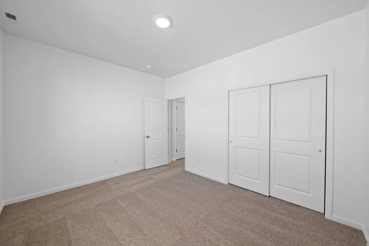 Neutral-toned carpet flooring, white painted walls, recessed ceiling lighting, and bi-fold closet doors