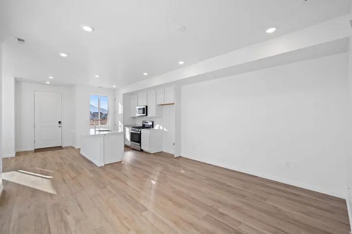 Open-concept living space with wood-finish flooring, recessed lighting, and a white kitchen island