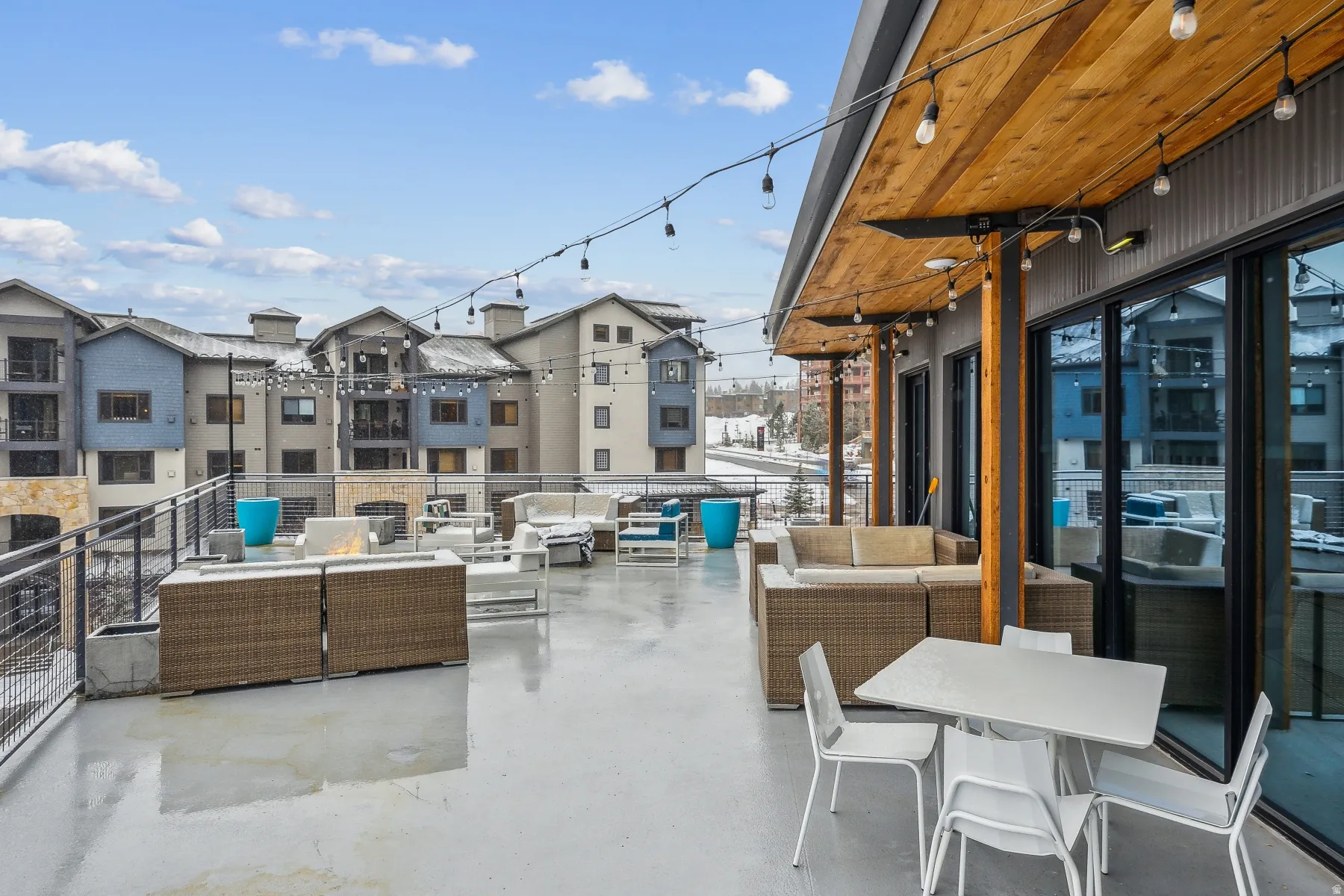 Spacious outdoor patio with string lighting, wood-finish ceiling, and expansive sliding glass doors