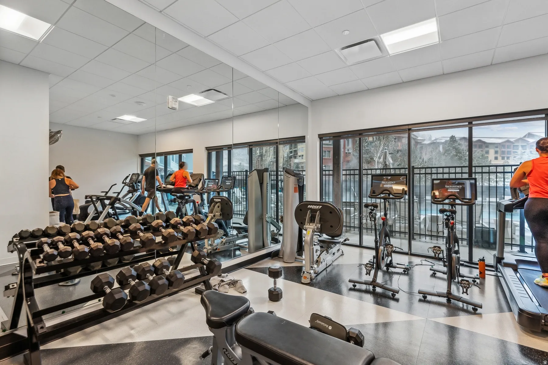 Fitness center featuring expansive wall mirrors, large windows, recessed lighting, and a durable flooring surface