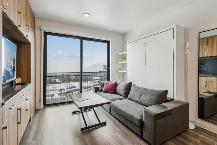 Full-height wood-finish cabinetry, built-in shelving, wall-mounted storage, and a large sliding glass door to a balcony