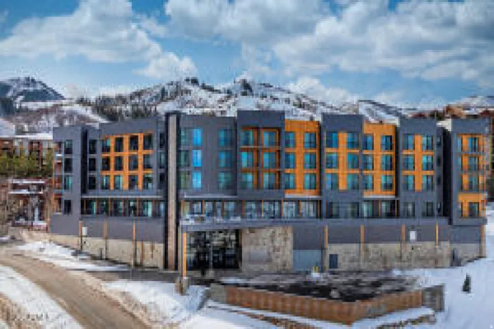 Modern multi-story building featuring a facade with mixed materials including wood-tone panels and dark siding