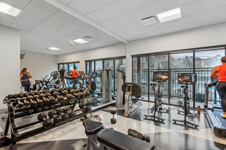 Fitness center featuring expansive wall mirrors, large windows, recessed lighting, and a durable flooring surface