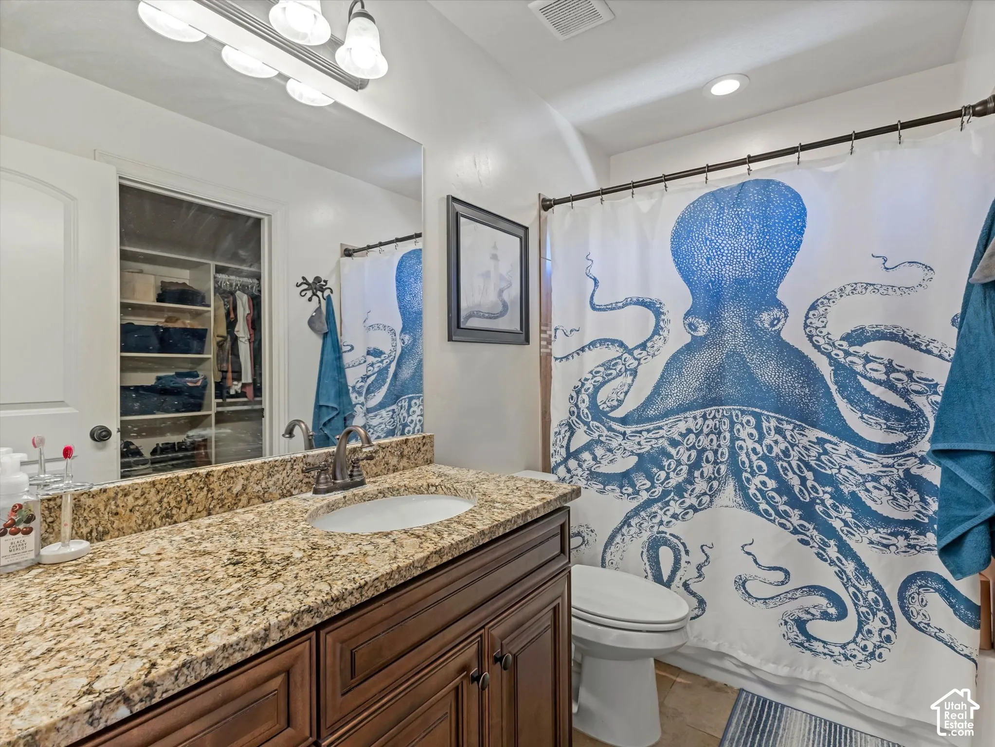 Granite countertop with an undermount sink, dark wood-finish cabinetry, and a full-width vanity mirror