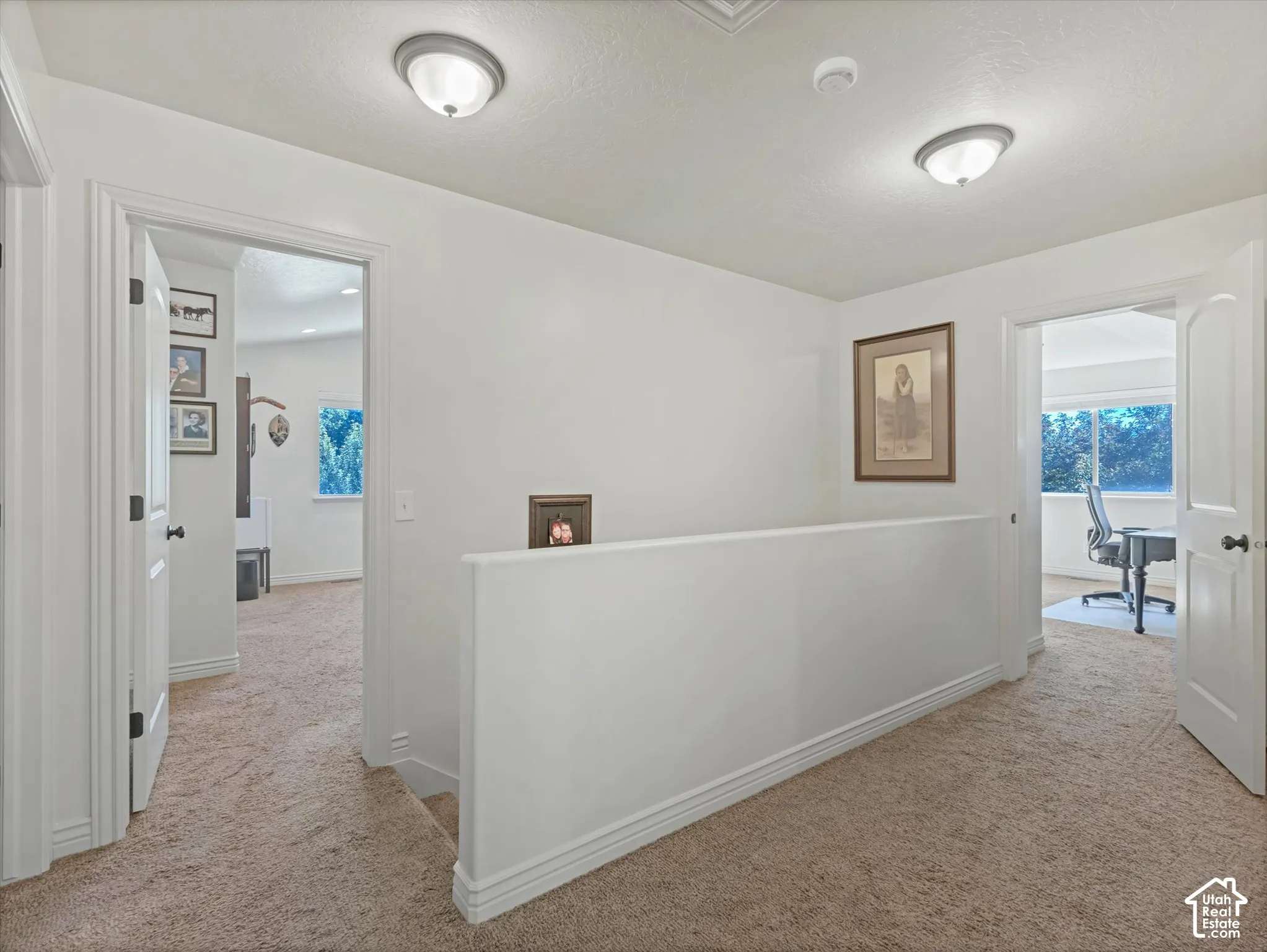 Carpeted hallway with white walls and trim, featuring two flush-mount ceiling lights