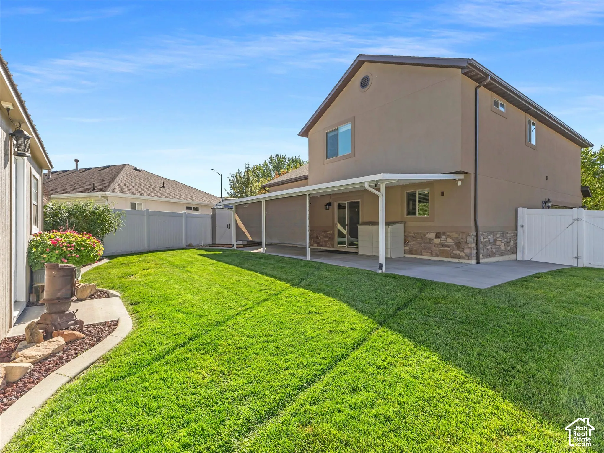 Expansive backyard featuring a covered patio, manicured lawn, and privacy fencing