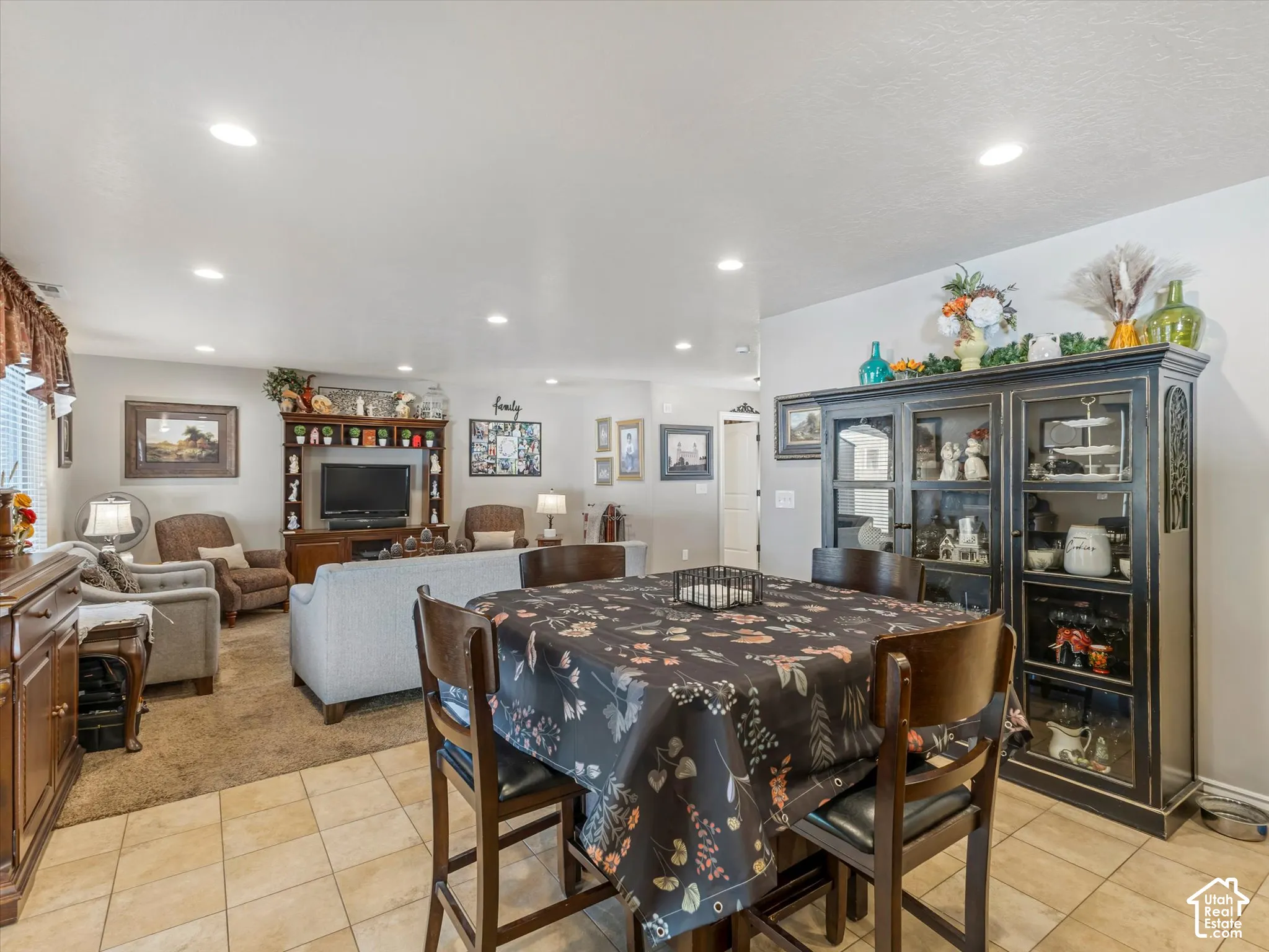 Recessed ceiling lighting, tiled flooring, wood-finish built-in entertainment center, and a display cabinet with glass doors
