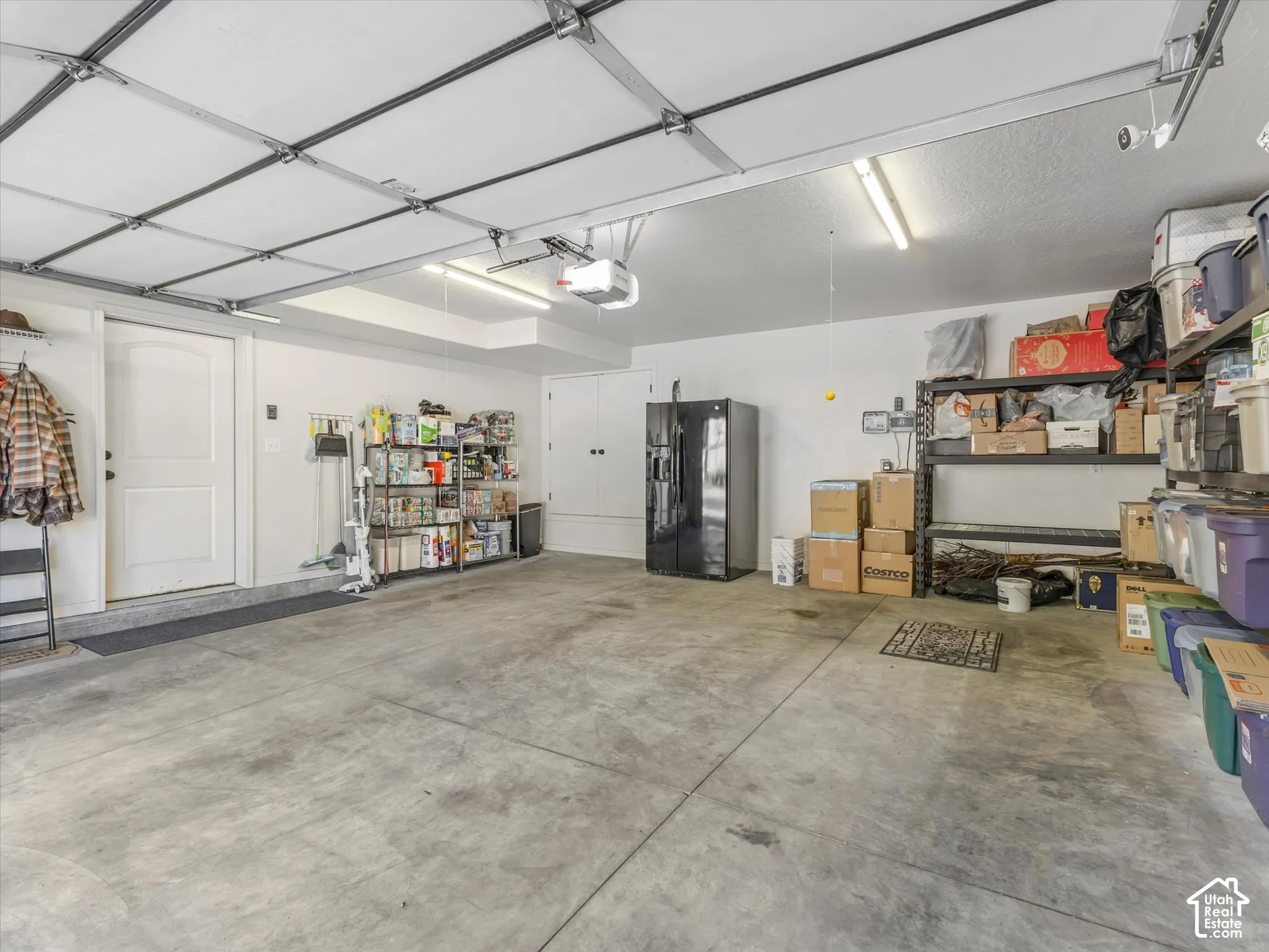 Two-car garage with concrete flooring, overhead fluorescent lighting, and a garage door opener system