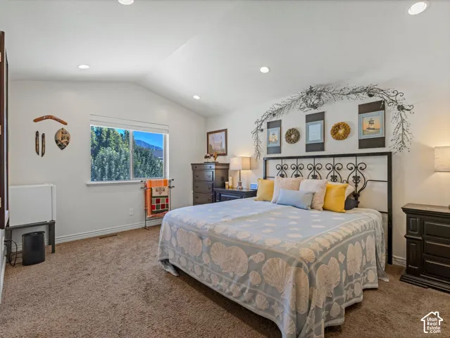 Vaulted ceiling with recessed lighting, large window, and wall-to-wall carpeting