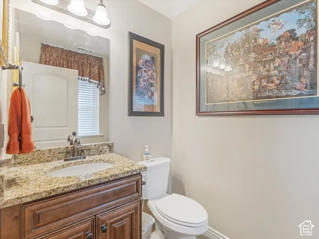 Granite countertop, wood-finish vanity, undermount sink, and wall-mounted mirror