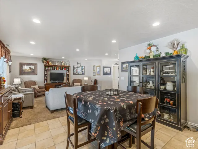 Recessed ceiling lighting, tiled flooring, wood-finish built-in entertainment center, and a display cabinet with glass doors