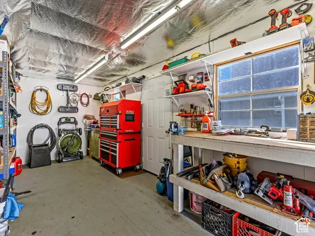 Workstation featuring a built-in workbench, wall-mounted shelving, and multiple fluorescent light fixtures