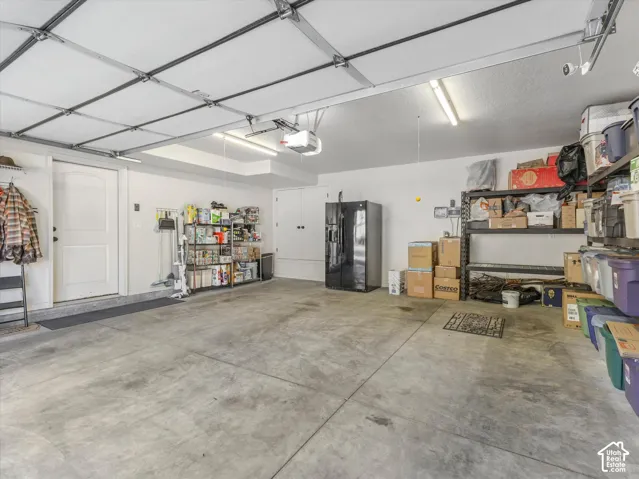 Two-car garage with concrete flooring, overhead fluorescent lighting, and a garage door opener system