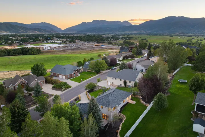 Expansive mountain backdrop, green fields, and a residential street with mature trees