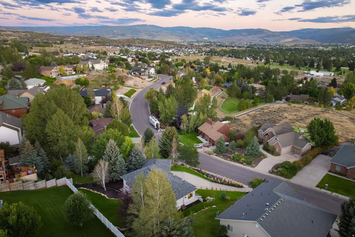 Aerial perspective showcasing residential properties with varied architectural styles, mature landscaping, and curved roadways