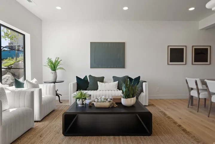 Recessed lighting illuminates an open-concept living area with light wood-finish flooring