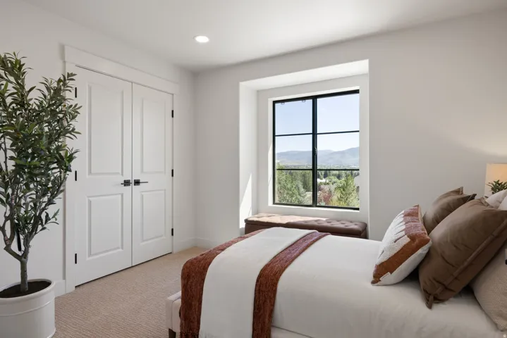 White interior walls, recessed ceiling lighting, a grid-pattern window with a mountain backdrop, and light-colored carpet flooring